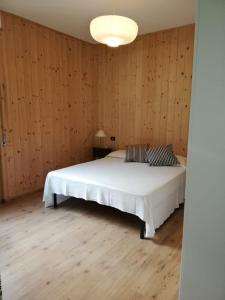 um quarto com uma cama branca e paredes de madeira em Casa di Vanna em Follonica