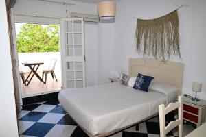 a bedroom with a bed and a balcony with a table at Hostal Los Rosales in Conil de la Frontera
