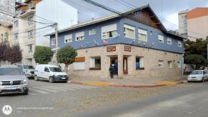 un hombre parado frente a un edificio azul en Hostería Sur en San Carlos de Bariloche
