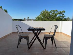 - une table et deux chaises sur la terrasse dans l'établissement Hostal Los Rosales, à Conil de la Frontera