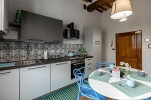 una cocina con armarios blancos y una mesa con sillas azules en La sosta di Arrigo, en Buonconvento