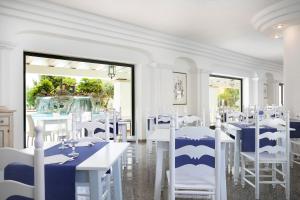 una sala da pranzo con tavoli bianchi e sedie bianche di Hotel Maria Rosaria a Orosei