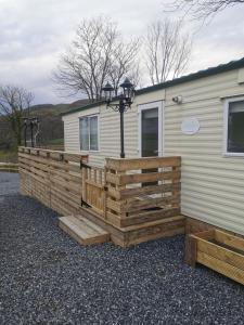 a mobile home with a wooden fence and a street light at FAB Caravan Holiday Home in Colmonell