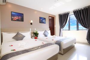 a hotel room with two beds and a window at Thành Nhân Hotel in Da Nang