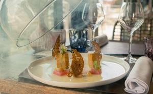 a plate of food on a table with wine glasses at Hôtel Restaurant Le Grand Large - Face à la plage - Ile de Ré in Rivedoux-Plage