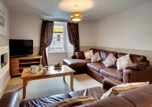 a living room with leather couches and a tv at Monicas House 8 Porthmeor Square in St Ives
