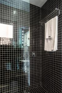 a black tiled bathroom with a shower and a mirror at Boxo Diani - Unique Beach Front Container Eco-Hotel in Diani Beach