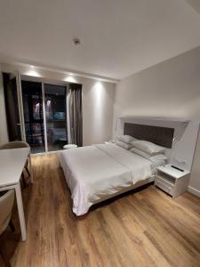 Un dormitorio con una gran cama blanca y una mesa en Royal panorama alliance batumi, en Batumi