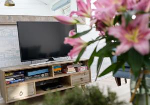 a flat screen tv on a wooden entertainment center with pink flowers at Sail Loft Studio in St Ives