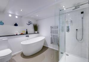 a white bathroom with a tub and a glass shower at Sail Loft Studio in St Ives