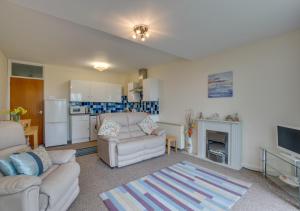 uma sala de estar com mobiliário branco e uma cozinha em Seacroft 6 Carthew Court em St. Ives
