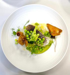 a white plate of food with peas and meat at Le Roscanvec in Vannes