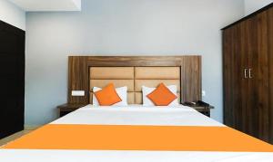 Queens Residency - Kochi في إرناكولام: غرفة نوم مع سرير كبير مع وسائد برتقالية