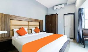 - une chambre avec un grand lit et des oreillers orange dans l'établissement Queens Residency - Kochi, à Ernakulam
