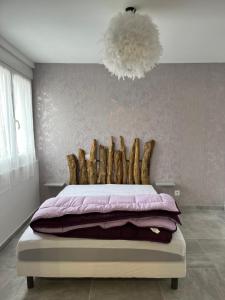 a bedroom with a bed with a headboard and a chandelier at Location saisonnière 1 in Clermont-lʼHérault