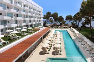 a hotel with a swimming pool with chairs and umbrellas at Iberostar Selection Santa Eulalia Adults-Only Ibiza in Santa Eularia des Riu