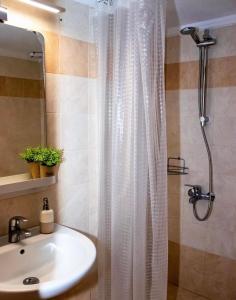 a bathroom with a white shower curtain and a sink at Starry Coast Apartments in Nea Potidaea