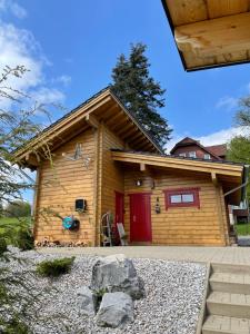 ブラウンラーゲにあるBlockhaus an der Skiwiese Braunlageの赤いドア付きのログキャビン