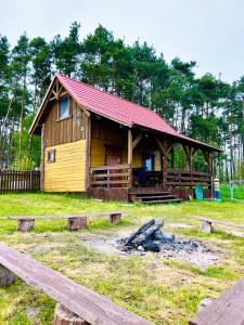 ein Blockhaus mit rotem Dach auf einem Feld in der Unterkunft Wiejskie Zacisze in Wiele