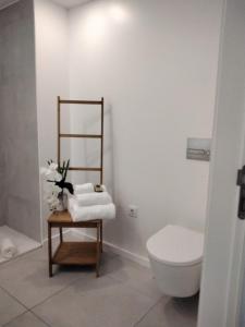 a bathroom with a toilet and a table with towels at PEARL HOUSE in Aveiro