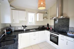 a kitchen with white cabinets and a black counter top at Villa berges landaises location vacances spacieuse Villa avec piscine chauffée capbreton in Capbreton