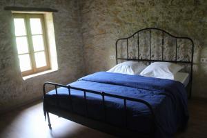een slaapkamer met een bed met een blauw dekbed en een raam bij Gîte - La Couderquié in Lautrec