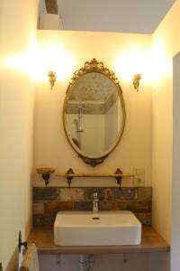 La salle de bains est pourvue d'un lavabo et d'un miroir mural. dans l'établissement Gîte - La Couderquié, à Lautrec
