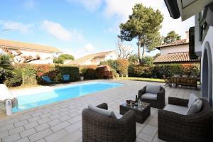 a patio with chairs and a swimming pool at Villa berges landaises location vacances spacieuse Villa avec piscine chauffée capbreton in Capbreton