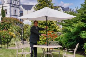 a man standing next to a table with an umbrella at Muckross Park Hotel & Spa in Killarney