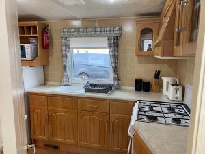 a small kitchen with a sink and a stove at The Atlas Everglade Caravan in Ingoldmells
