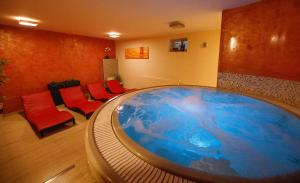 una gran bañera en una habitación con sillas rojas en Wellness Pension 7 en Harrachov