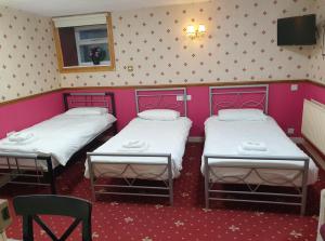 two beds in a room with pink walls at Lakes Lodge Windermere in Windermere