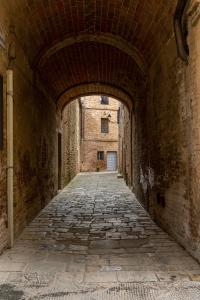 an alley way in an old building with an archway at La sosta di Arrigo in Buonconvento