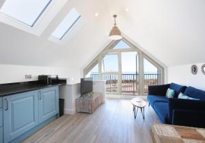 a living room with a blue couch and a large window at Old Coastguard Station in Dunbar