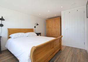 Un dormitorio con una gran cama de madera con sábanas blancas. en Old Coastguard Station, en Dunbar