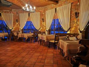 a restaurant with tables and chairs in a room with windows at Meškių dvarkiemis in Šiauliai
