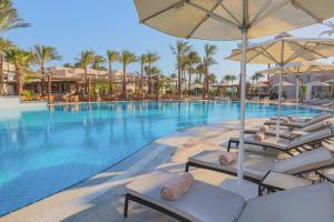 a pool at a resort with chairs and umbrellas at Iberotel Makadi Beach in Hurghada