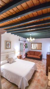 - une chambre avec un grand lit blanc et un canapé dans l'établissement LA ALDABA, antigua casa de labor, à Almagro