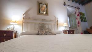 a bedroom with a large white bed and two lamps at LA ALDABA, antigua casa de labor in Almagro