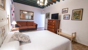 - une chambre avec un lit blanc et un canapé dans l'établissement LA ALDABA, antigua casa de labor, à Almagro
