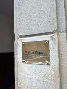 um sinal na lateral de um edifício branco em Maison Riquet em Castelnaudary
