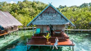 Eine Frau steht auf einem Holzsteg im Wasser in der Unterkunft Methos Homestay - Raja Ampat in Yennanas Besir