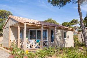 a tiny house with a porch and a fence at Camping Le Camp Du Domaine in Bormes-les-Mimosas