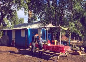 Dois homens numa mesa de piquenique em frente a uma casa. em Lircaydomohostal - Domo 40m2 para 4 personas em Talca