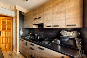 una cocina con armarios de madera y fregadero en Apartament Zakopane utrzymany w stylu góralskiej chaty, en Zakopane