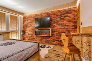 1 dormitorio con pared de ladrillo, cama y TV en Apartament Zakopane utrzymany w stylu góralskiej chaty, en Zakopane