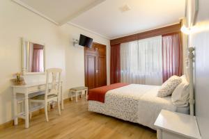 a bedroom with a bed and a desk and a table at Hotel América Ferrol in Ferrol