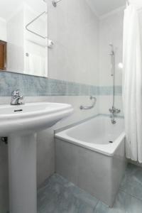Hotel América Ferrol في فيرول: حمام أبيض مع حوض وحوض استحمام