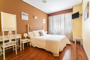 sypialnia z łóżkiem, biurkiem i oknem w obiekcie Hotel América Ferrol w mieście Ferrol
