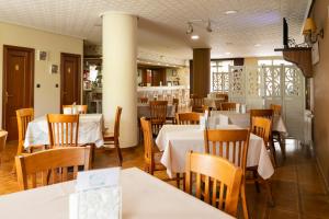restauracja z białymi stołami i drewnianymi krzesłami w obiekcie Hotel América Ferrol w mieście Ferrol